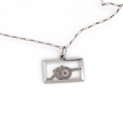 Antique platinum diamond cannon charm displayed beautifully on a chain inside.