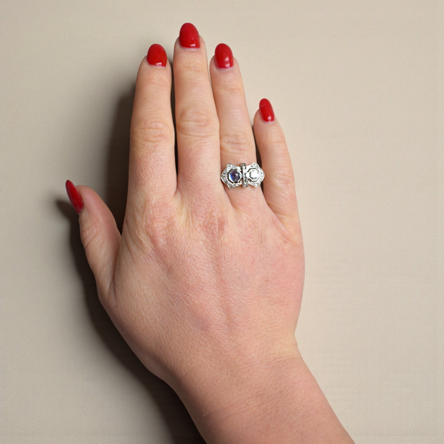 The hand of a woman wearing an antique French Art Deco sapphire and diamond engagement ring on her finger.