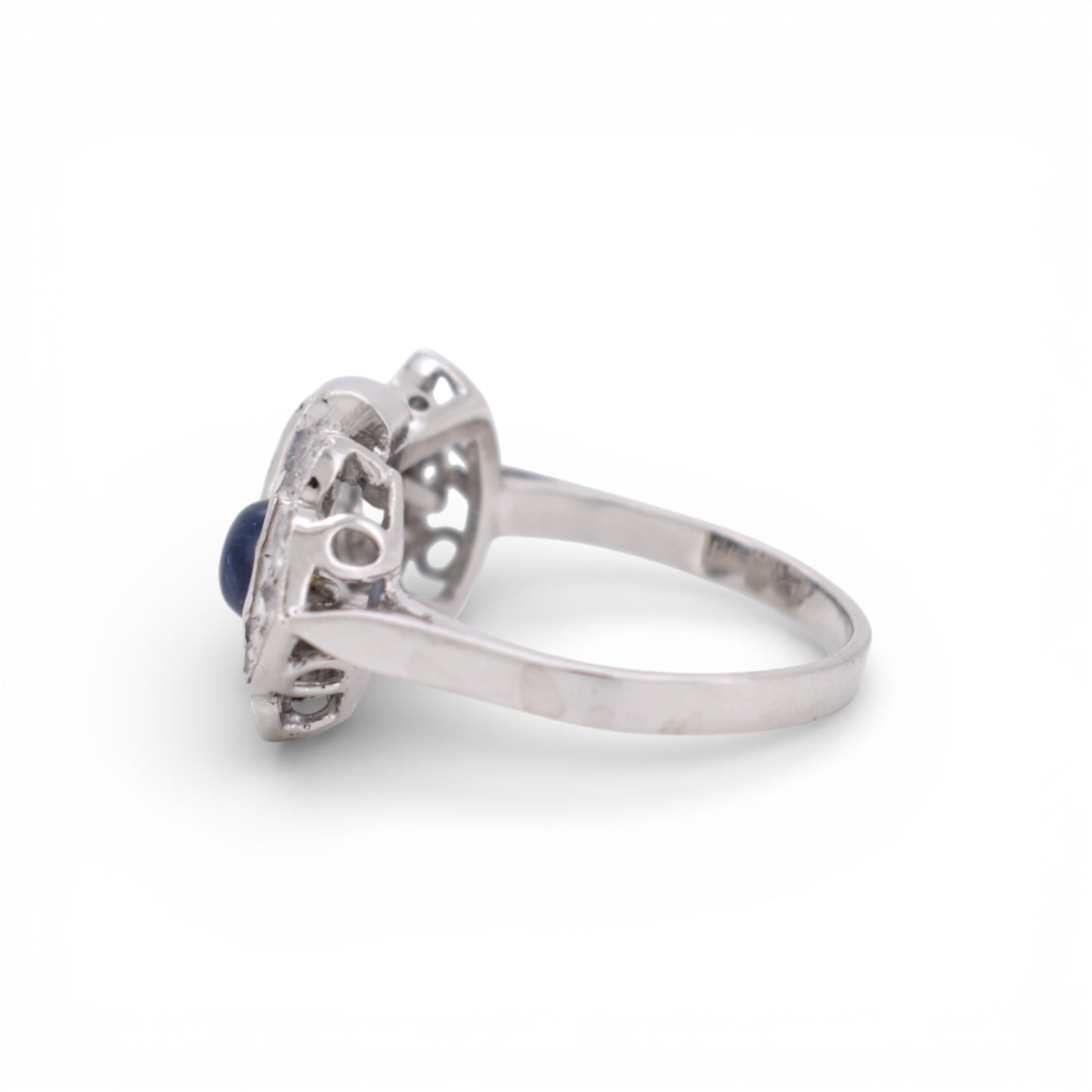 Antique 18K white gold ring with sapphire and diamonds resting on a neutral background.
