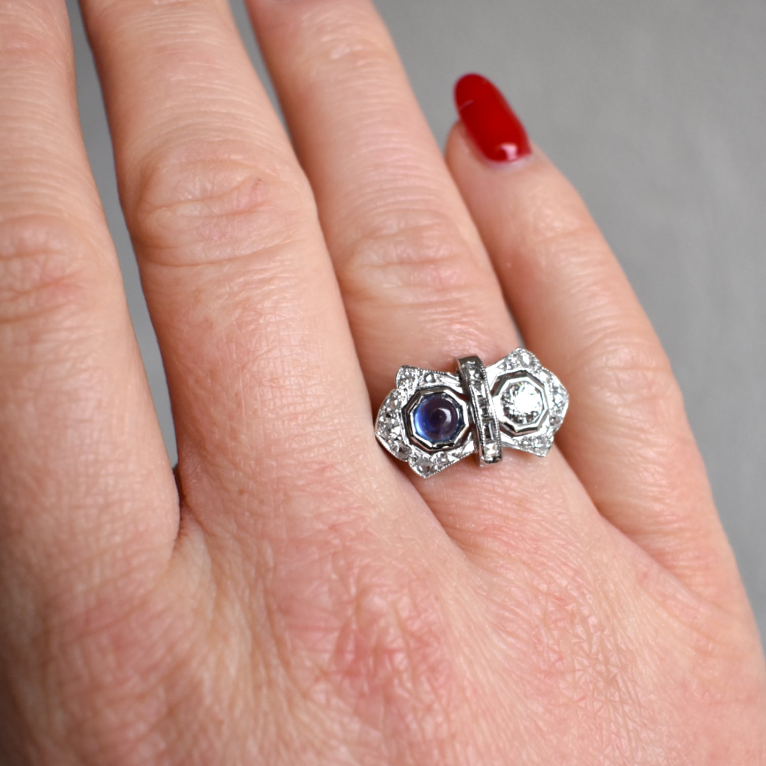 Woman wearing an antique French Art Deco sapphire and diamond engagement ring on her finger.