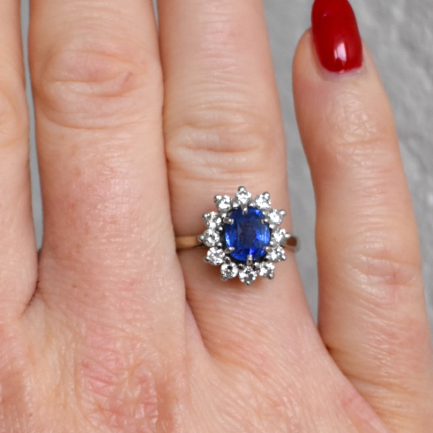 sapphire and diamond halo engagement ring worn on a hand in a natural light
