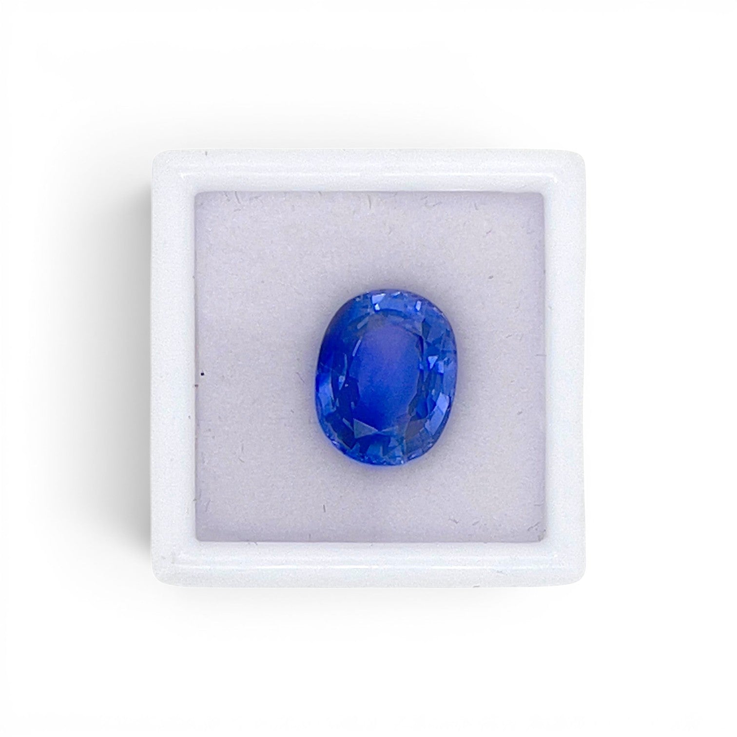 Loose 5.67 carat natural oval cushion cut blue sapphire gemstone from Ceylon (Sri Lanka) displayed inside a luxury presentation gem box by Antique Jewelry Finds.