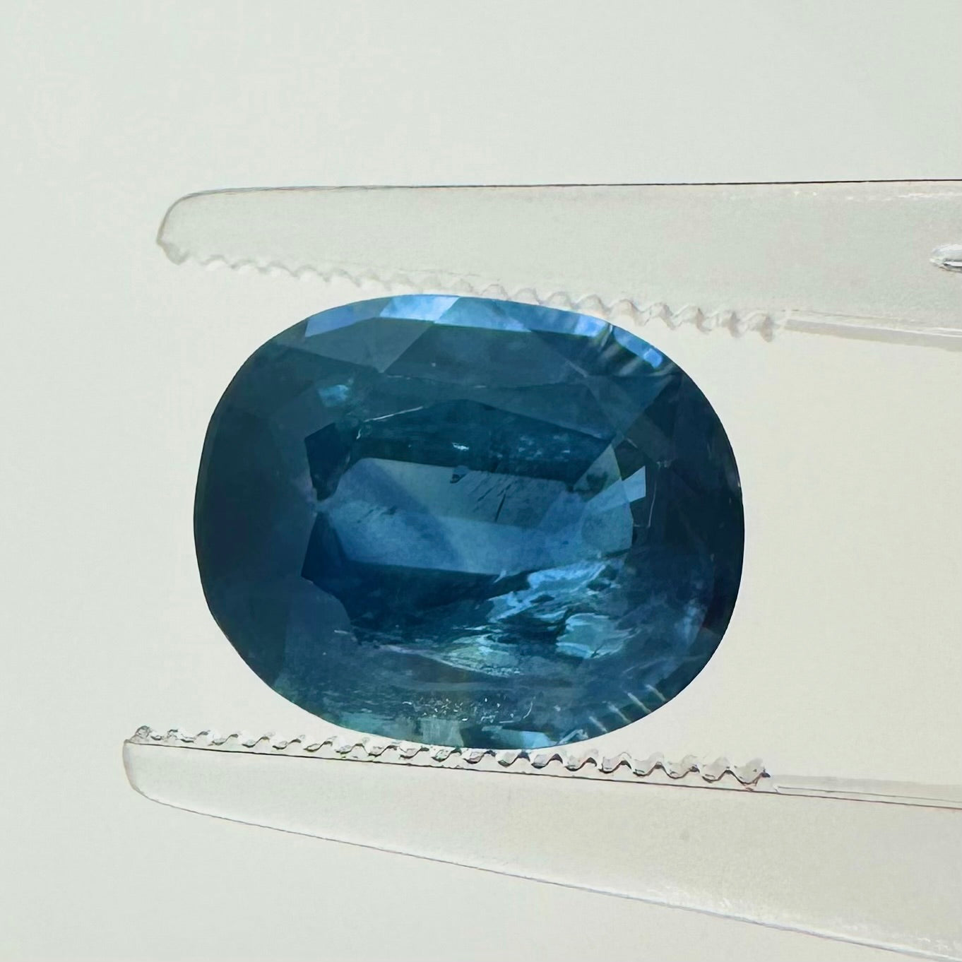 Extreme macro face shot of the 3.62ct natural blue sapphire showcasing its elegant oval cushion shape, smooth corners, and brilliant faceting.