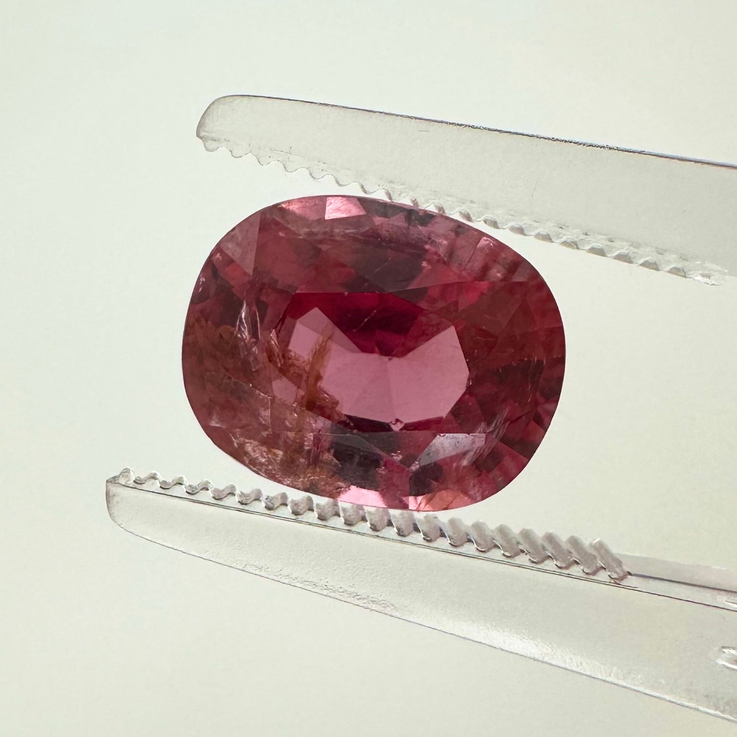 Extreme macro face shot of the 2.40ct natural electric pink orange spinel showcasing its exceptional oval cushion cut and crisp facets.