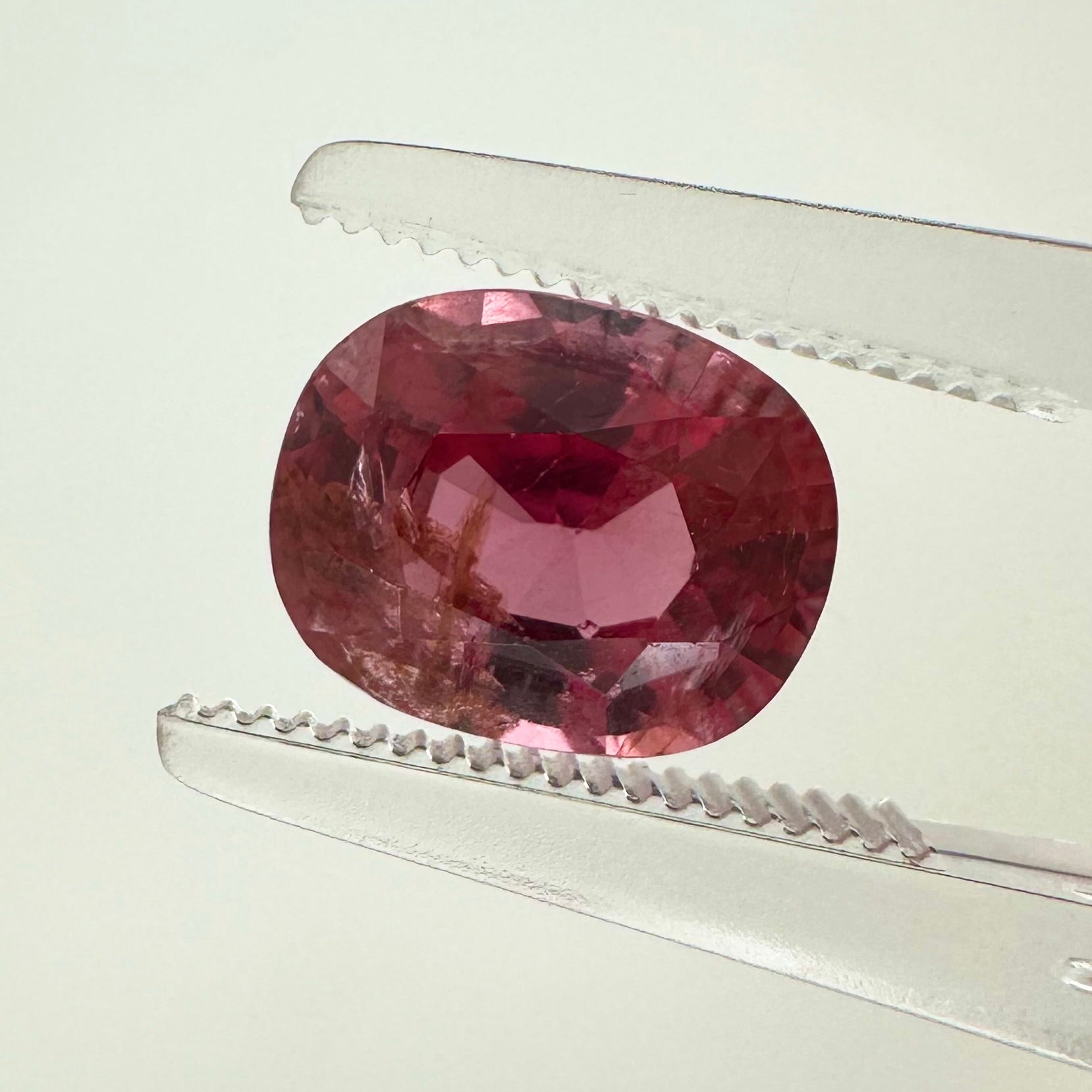 Extreme macro face shot of the 2.40ct natural electric pink orange spinel showcasing its exceptional oval cushion cut and crisp facets.