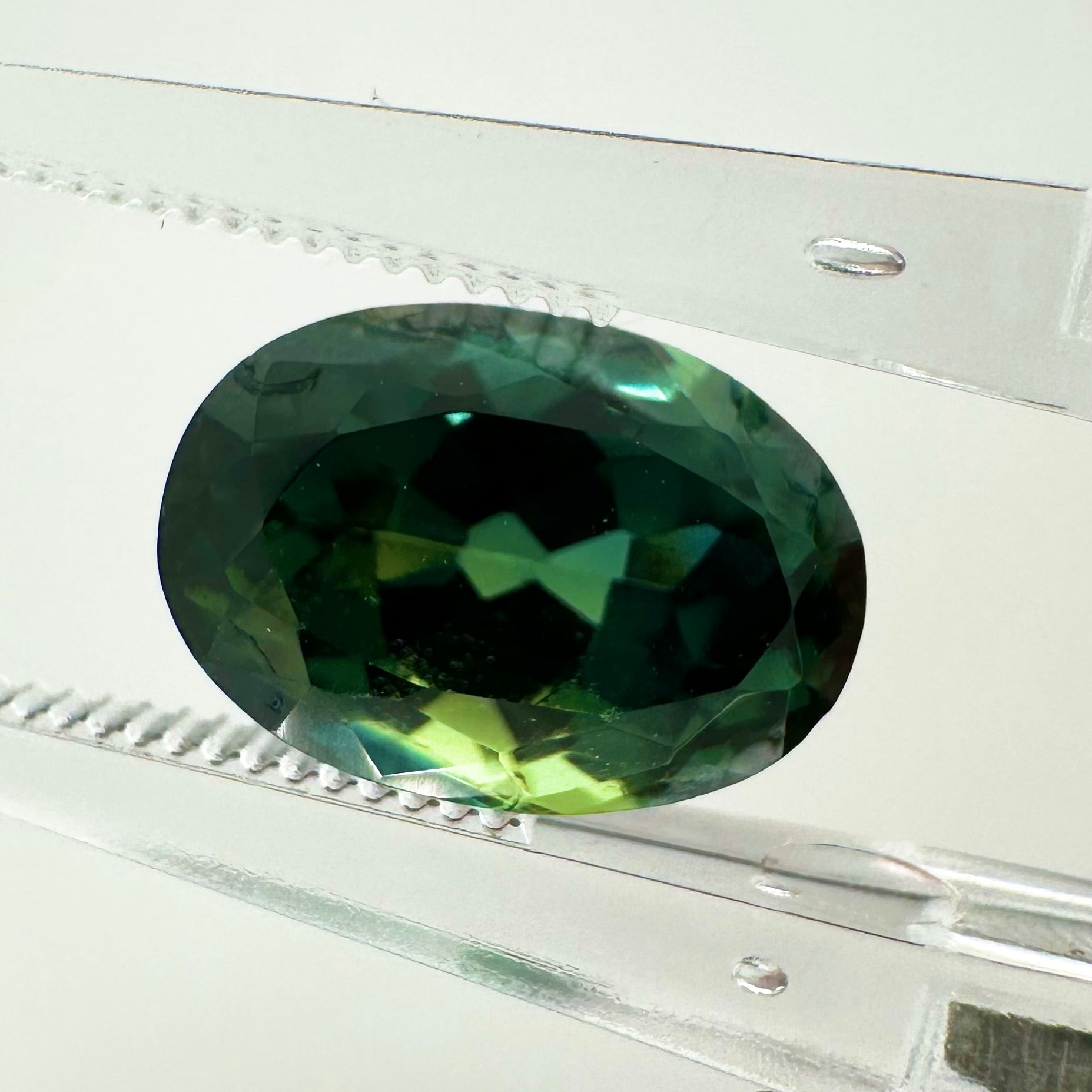 Extreme macro face shot of the 3.55ct natural green sapphire showcasing its elegant oval cut and crisp, brilliant facets.
