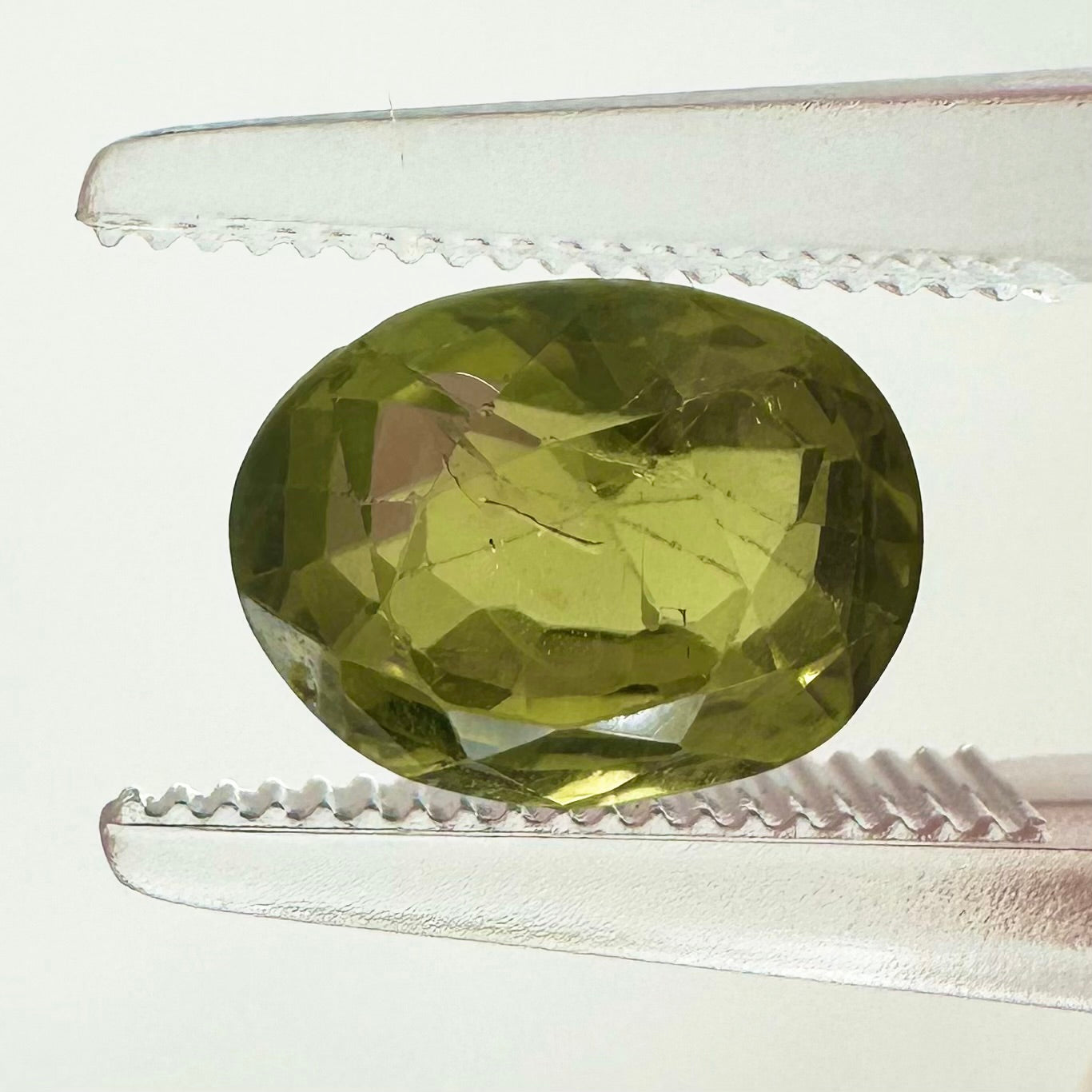 Extreme macro face shot of the 2.47ct natural green Ceylon sapphire showcasing its elegant oval cut and crisp, brilliant facets.