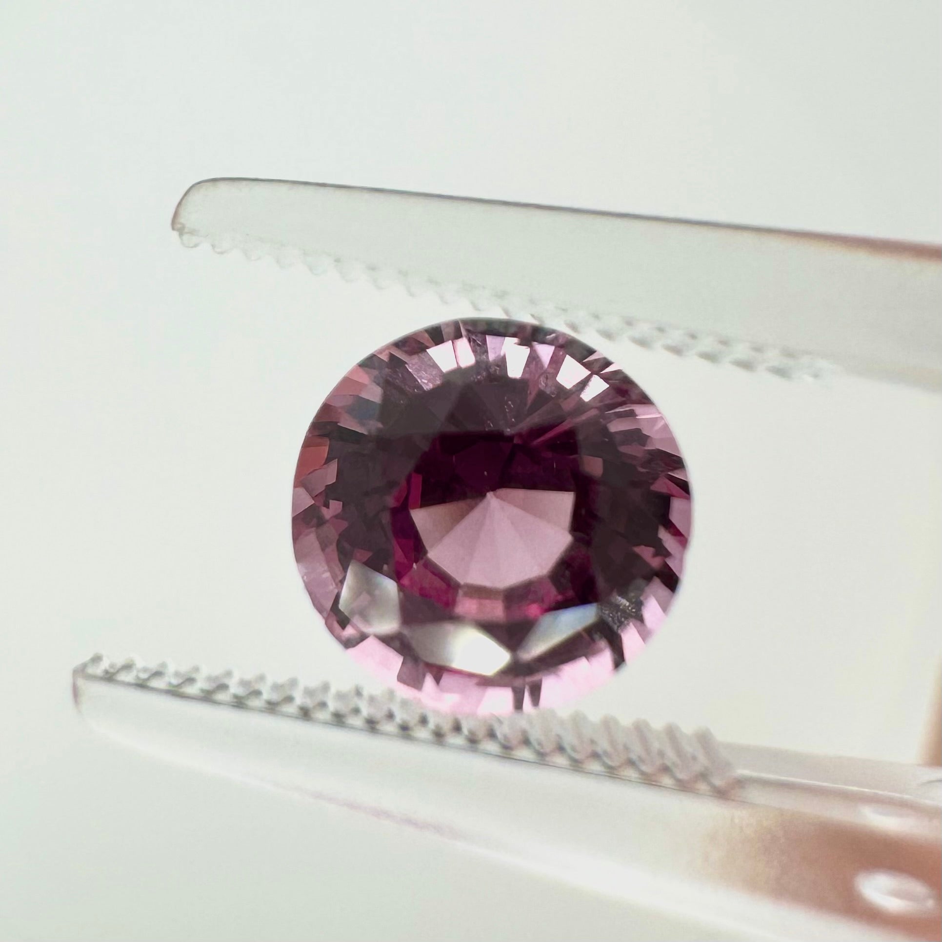 Extreme macro face shot of the 1.75ct natural vivid pink spinel showcasing its exceptional brilliant round cut and crisp facets.