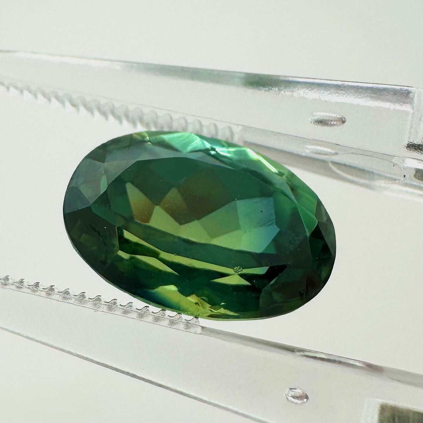Side profile view of the unheated 3.55 carat green oval sapphire highlighting its perfect symmetry and pavilion depth.