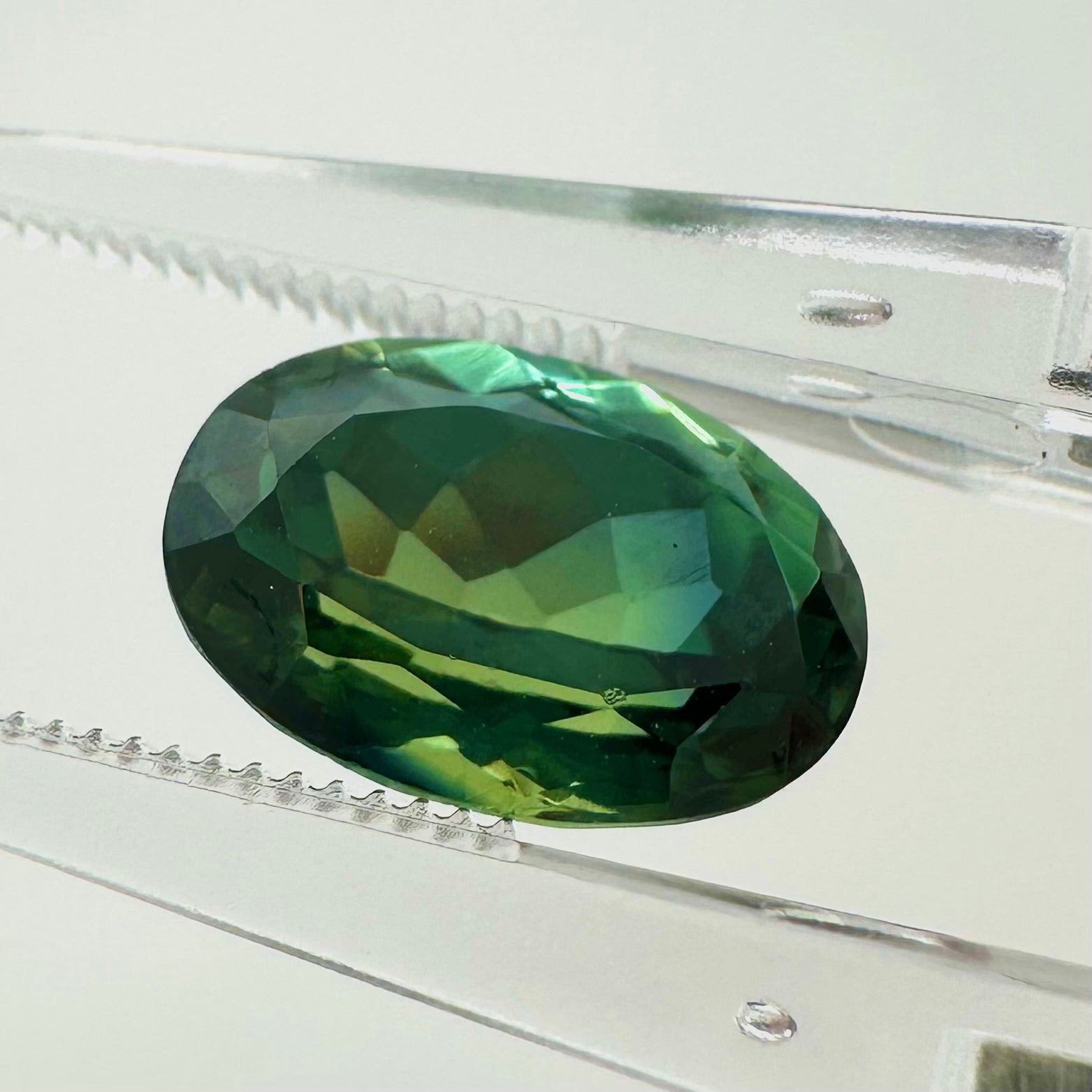 Side profile view of the unheated 3.55 carat green oval sapphire highlighting its perfect symmetry and pavilion depth.