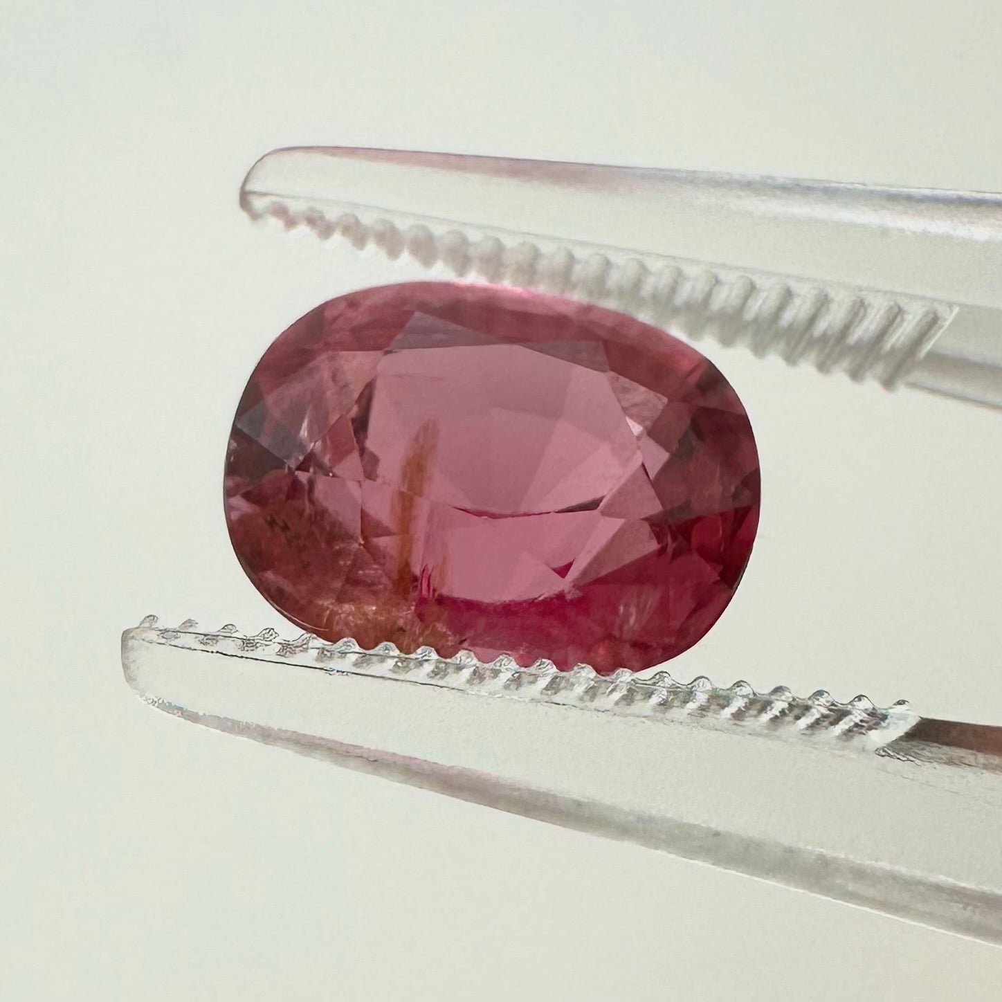 Side profile view of the unheated 2.40 carat Vietnam electric pink orange spinel highlighting its perfect symmetry and pavilion depth.