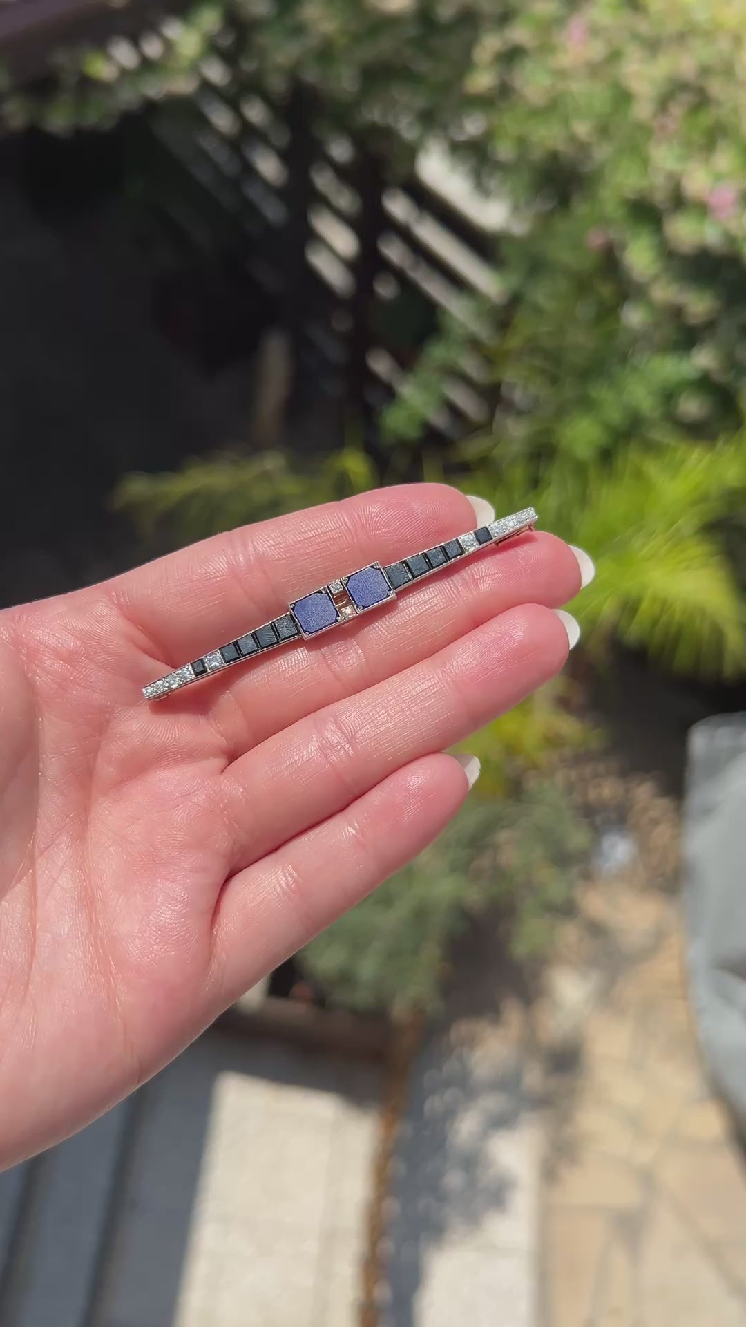 High-definition video capturing the intense blue of the lapis lazuli, the sleek black luster of the onyx, and the ultra-bright, fiery brilliance of the D-color diamonds on the geometric 1920 Art Deco platinum bar brooch in motion.