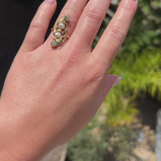 High-definition video capturing the soft iridescent glow of the natural pearls, the fiery brilliance of the 0.80-carat old-cut diamonds, and the fluid, organic lines of the circa 1910 Antique Art Nouveau 18k gold ring in motion.