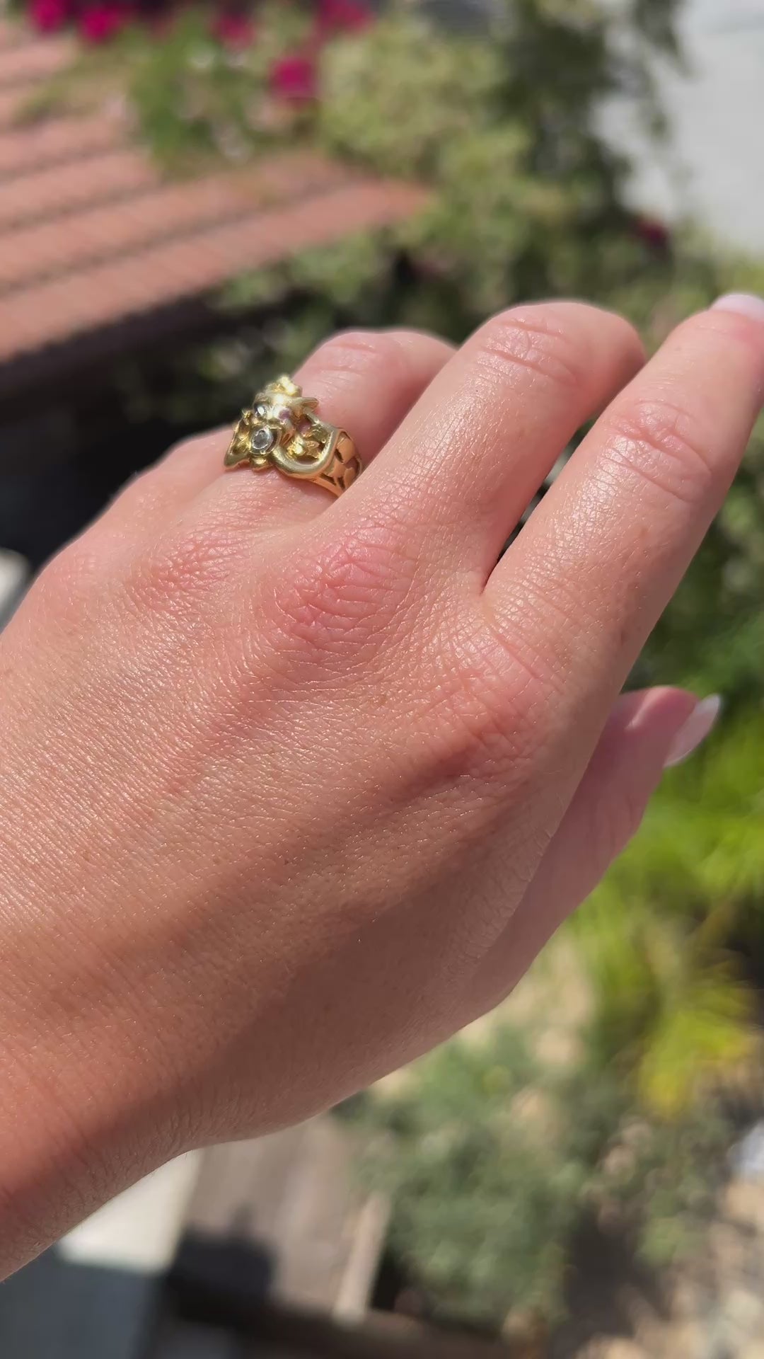 High-definition video capturing the intricate, sculptural details of the 18k gold gargoyle, the sharp red glint of the ruby eyes, and the fiery flash of the diamond in its mouth on the circa 1910 Antique Art Nouveau ring in motion.
