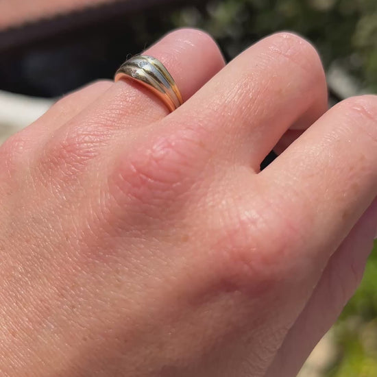High-definition video capturing the iconic intertwined bands of the 18k three-tone gold Trinity style ring, the sharp fiery brilliance of the 3 diamonds, and the authentic engraved signature and serial number on the shifting polished surfaces in motion.