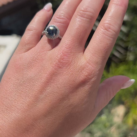 High-definition video capturing the deep blue flashes of the sapphire, the fiery brilliance of the surrounding diamond halo, and the modern polished luster of the circa 2000 contemporary 18k gold ring in motion.
