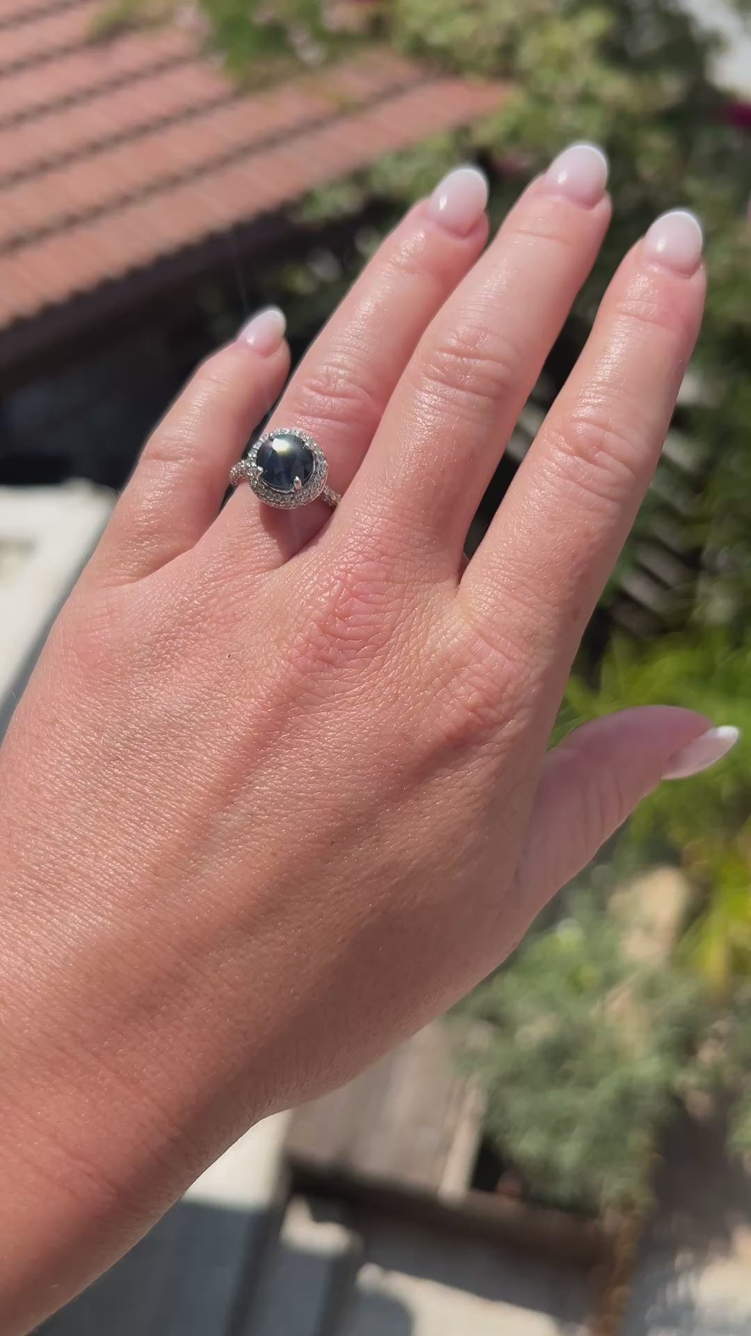 High-definition video capturing the deep blue flashes of the sapphire, the fiery brilliance of the surrounding diamond halo, and the modern polished luster of the circa 2000 contemporary 18k gold ring in motion.