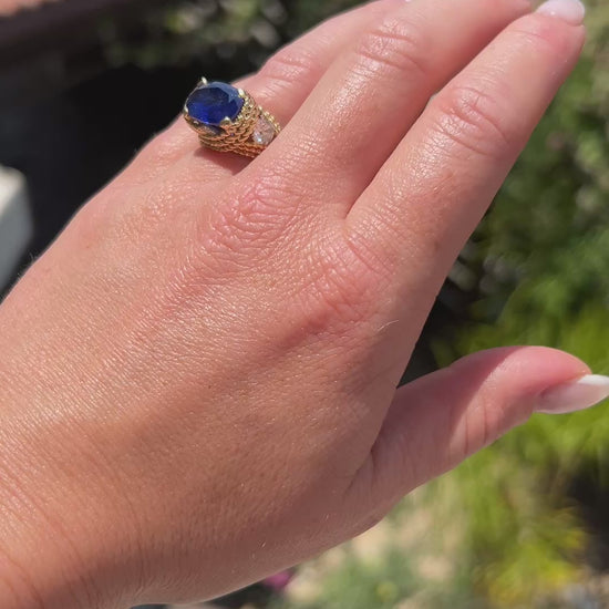 High-definition video capturing the velvety blue flashes of the 5.20ct unheated Ceylon sapphire, the fiery diamond sparkle, and the rich texture of the braided 18k gold Mid-Century ring in motion.