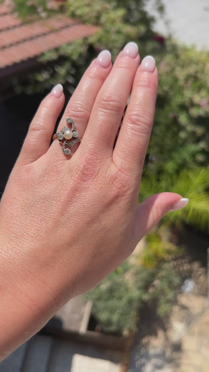 High-definition video capturing the soft iridescent glow of the antique pearl, the fiery brilliance of the old-cut diamonds, and the fluid, organic curves of the 1910 Art Nouveau 18k gold and platinum ring in motion.