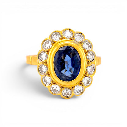 Vintage 1980s French 18k gold marguerite cluster ring with a 2ct blue sapphire and brilliant diamond halo by Antique Jewelry Finds.