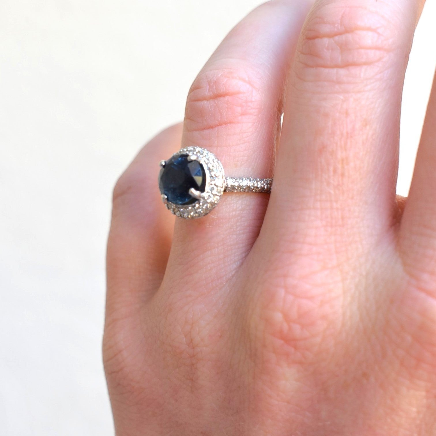 Macro shot of 3 carat natural blue sapphire centered in a geometric double halo setting